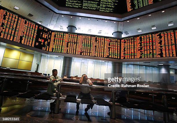 Investors monitor the stock prices displayed on the Kuala Lumpur Composite Index at the RHB Investment Bank trading gallery on May 7, 2013 in Kuala...