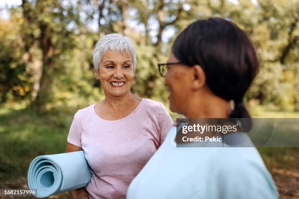 zwei ältere freundinnen mit yogamatte in der natur - alte und junge lesbische frauen stock-fotos und bilder