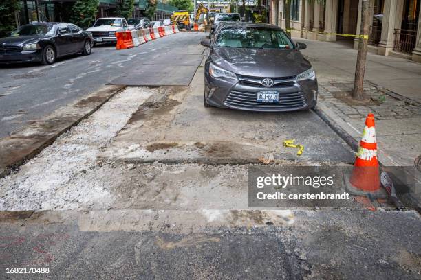 auto in einer straße geparkt, in der der asphalt repariert werden muss - straßenbau stock-fotos und bilder