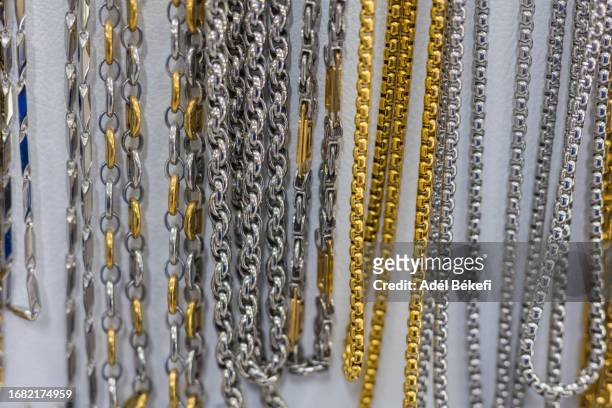 gold and silver colored  necklaces hanging for sale at the market - bijoux or stock-fotos und bilder