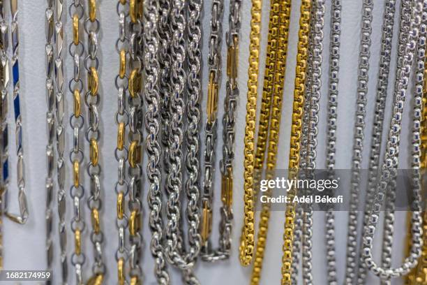 gold and silver colored  necklaces hanging for sale at the market - bijou - fotografias e filmes do acervo