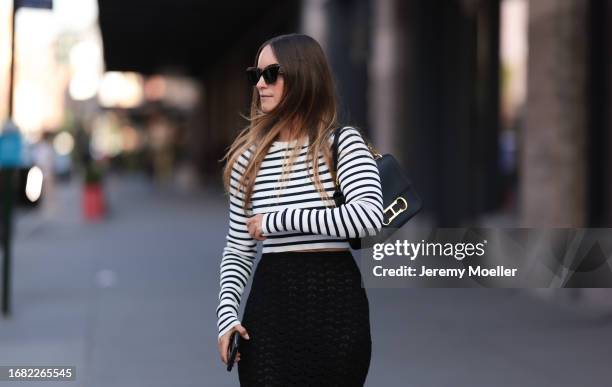 Charlotte Groeneveld is seen wearing black sunglasses; a black/white striped long-sleeved top; a black, perforated, high-waisted cut maxi skirt; a...