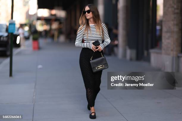 Charlotte Groeneveld is seen wearing black sunglasses; a black/white striped long-sleeved top; a black, perforated, high-waisted cut maxi skirt; a...