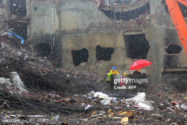 Bangladeshi rescue personnel carry stretchers with the remains of garment workers from the site of the collapsed Rana Plaza garment building as heavy...