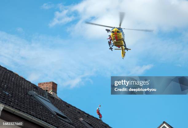 un hélicoptère de sauvetage de l’adac descend en rappel un médecin urgentiste au-dessus d’une zone résidentielle. à la périphérie de hambourg - rope high rescue photos et images de collection