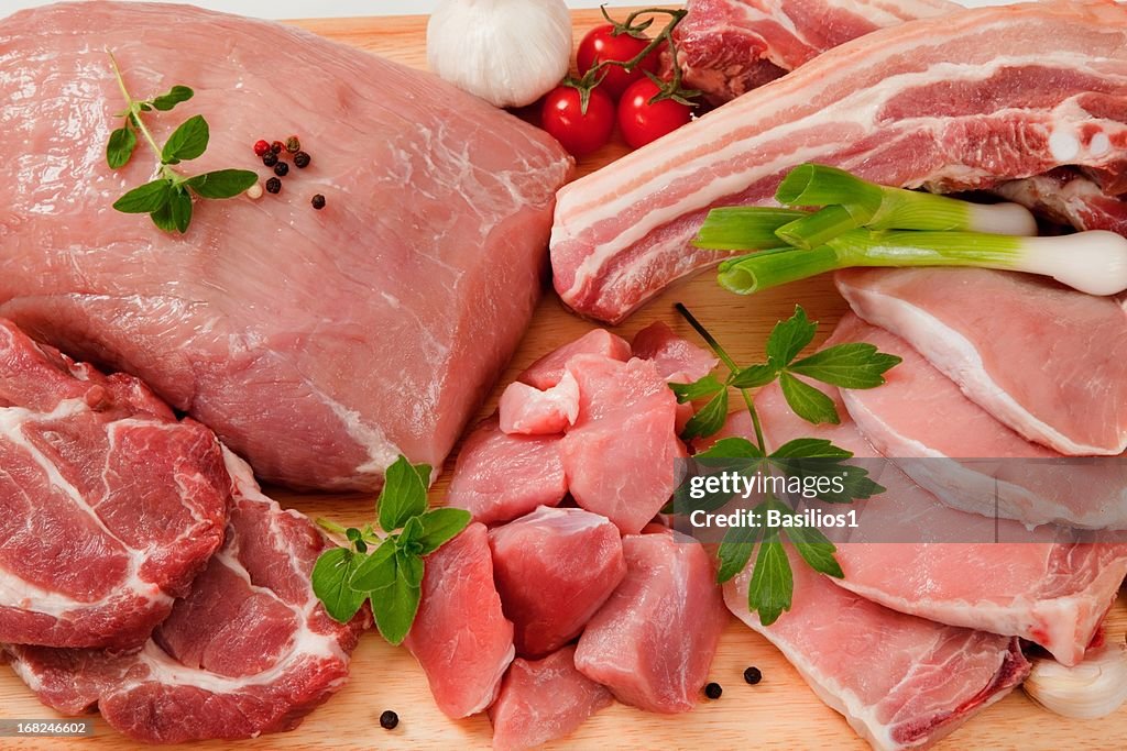 Raw cuts of pork meat on a wooden chopping board