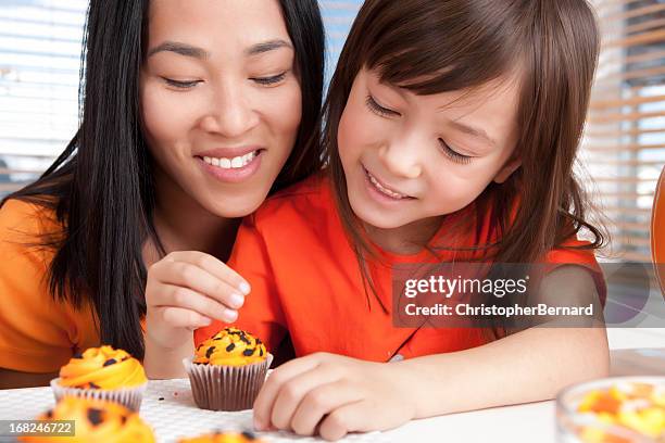 mutter und tochter backen halloween-cupcakes - 2 people back asian stock-fotos und bilder