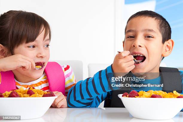 young boy and girl enjoying their breakfast before school - school breakfast stock pictures, royalty-free photos & images