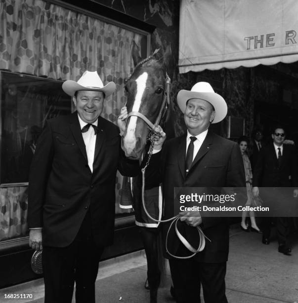 Entertainers Tex Ritter and Gene Autry pose for a portrait with the horse named "Country Music" which was the door prize of the day for the Country...