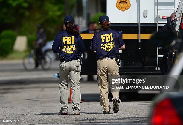 Forensic personnel walk in front of the house where three women were held captive for a decade on May 7, 2013 in Cleveland, ohio. Three brothers have...