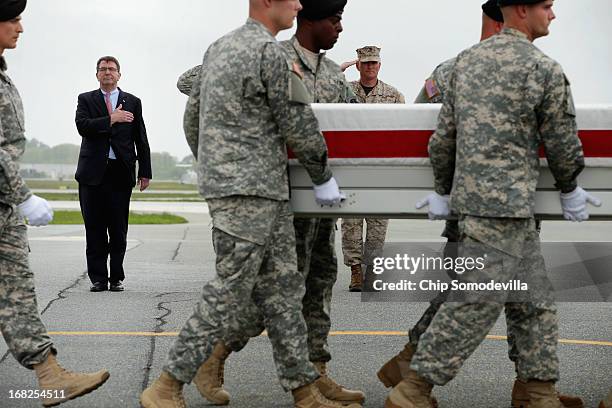 Deputy Secretary of Defense Ashton Carter and Marine Col. Christian Cabaniss salute as a U.S. Army carry team carries the flag-draped transfer case...