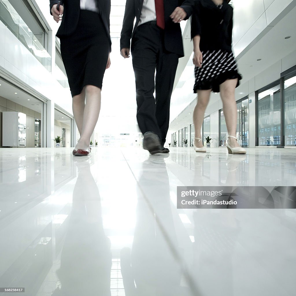 Lower half photo of business people walking in white hall