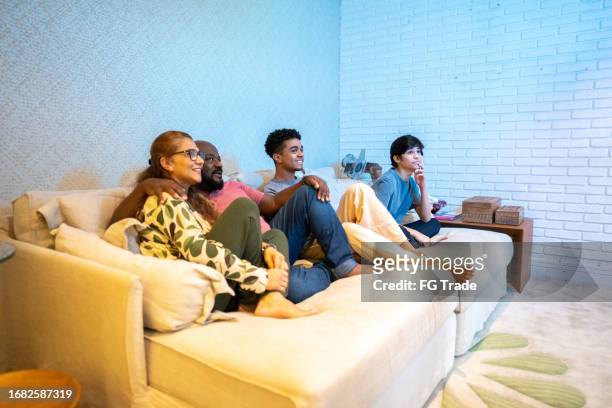 family watching tv together at home - family watching television stock pictures, royalty-free photos & images