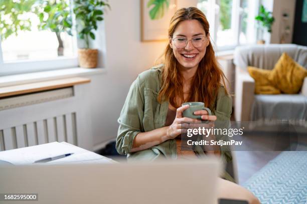 donna caucasica dai capelli rossi con vitiligine che beve caffè mentre ha una videochiamata tramite laptop - sistema immunitario foto e immagini stock