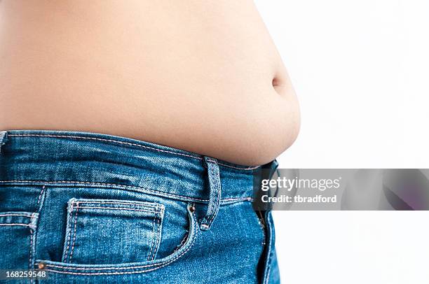 womans belly over tight blue jeans - too small stockfoto's en -beelden