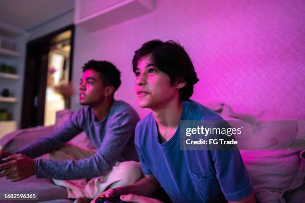 brothers playing video game at home - boy at television stockfoto's en -beelden