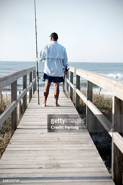 surf fisherman looking at the sea holding a fish - surf casting stock pictures, royalty-free photos & images