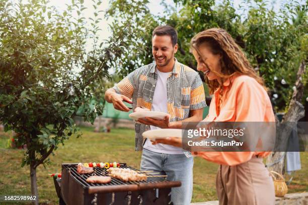 young caucasian couple making barbecue - couple grilling stock pictures, royalty-free photos & images