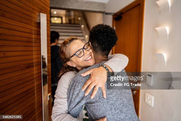aunt greeting nephew arriving at home - nephew stock pictures, royalty-free photos & images