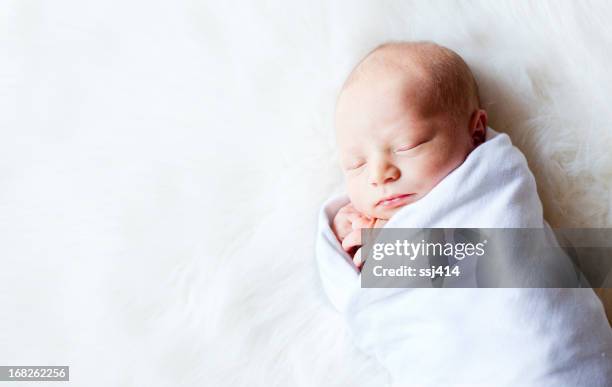 newborn baby swaddled while on fur rug - babydeken stockfoto's en -beelden