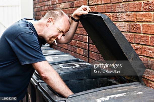 scruffy homeless man investigates dumpster - rea001 stock pictures, royalty-free photos & images