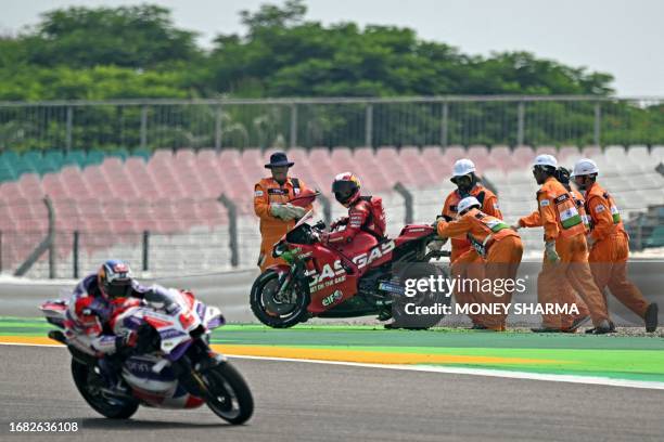 Track marshalls push the bike of Gasgas Factory Racing Tech3's Spanish rider Pol Espargaro as Prima Pramac's French rider Johann Zarco rides past...