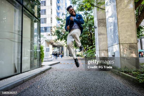 aufgeregter geschäftsmann im mittleren erwachsenenalter feiert im freien - faust in die luft stoßen stock-fotos und bilder