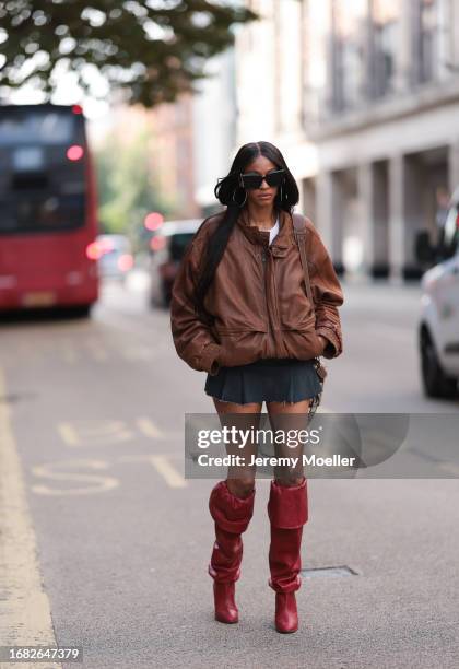 Fashion Show Guest was seen wearing red high heels, a short grey skirt, a white top, a beige Loewe Bag, dark Yve Saint laurent shades and an...