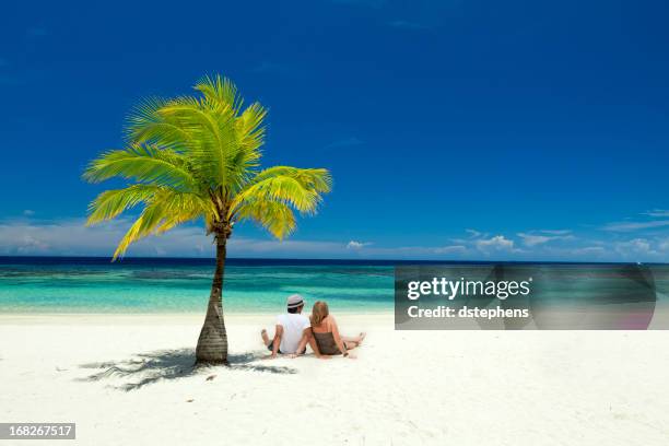 couple sitting on tropical beach - roatan stock pictures, royalty-free photos & images