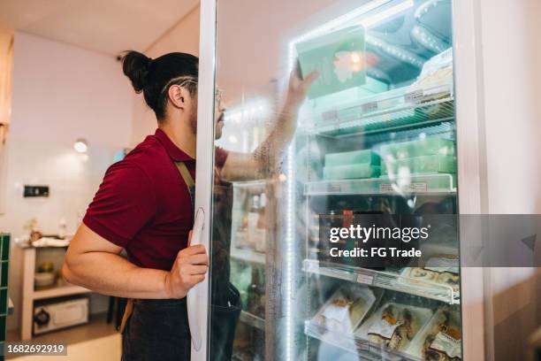 business owner arranging refrigerator in a store - freezer stock pictures, royalty-free photos & images