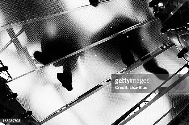 people moving up glass staircase.nyc.black and white. - black and white stock pictures, royalty-free photos & images