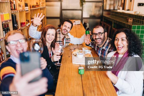 happy friends taking a selfie at a restaurant - online happy hour stock pictures, royalty-free photos & images