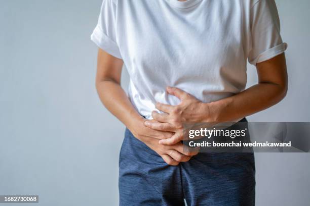 woman holds her lower abdomen in pain. - people peeing 個照片及圖片檔