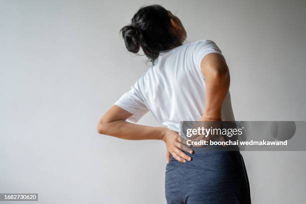 woman with hand on lower back. - human back stock pictures, royalty-free photos & images