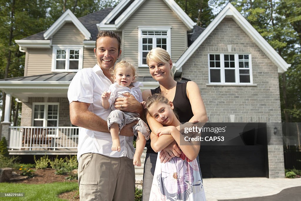 Happy Family In Front Of Their New House