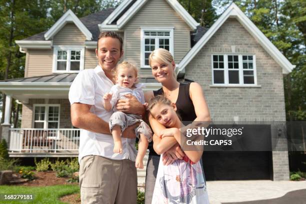 happy family in front of their new house - family of four in front of house stock pictures, royalty-free photos & images