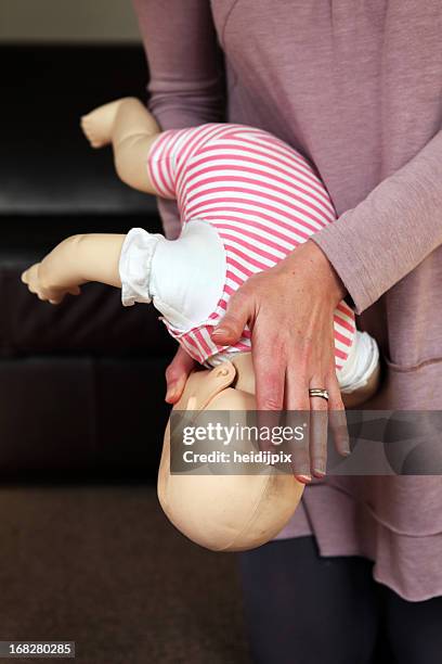 a woman trains to help a baby that is choking - first aid training stock pictures, royalty-free photos & images