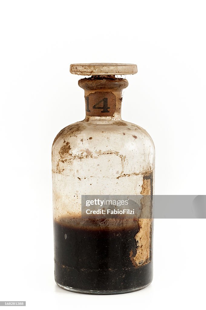 An old glass bottle half filled with brown poison