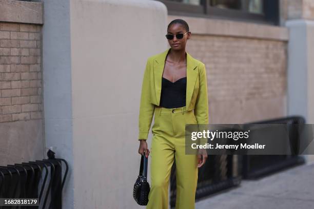 Guest is seen outside Brandon Maxwell show wearing black sunnies with golden hardware, black bustier top, lime green cropped blazer with matching low...