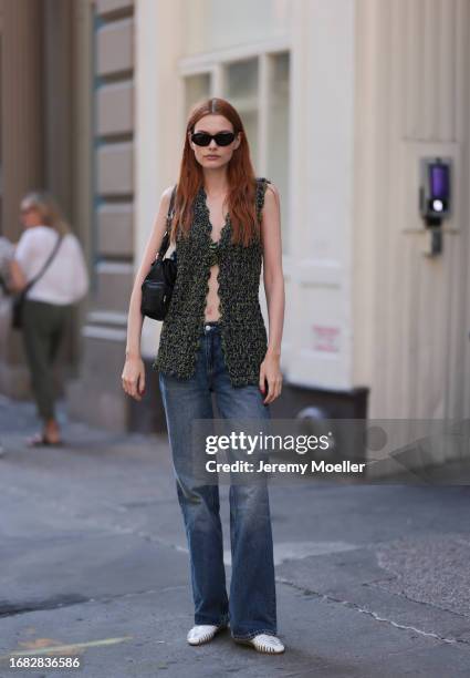 Guest is seen outside Brandon Maxwell show wearing black round sunnies, green crocheted vest with open front, low waist pair of jeans and white net...