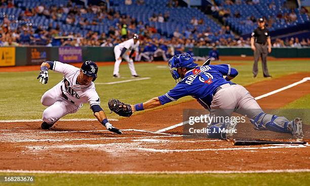 Catcher J.P. Arencibia of the Toronto Blue Jays stretches but does not initially tag Sean Rodriguez of the Tampa Bay Rays during the game at...