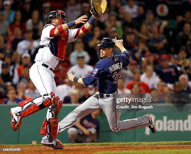 Justin Morneau of the Minnesota Twins scores as Jarrod Saltalamacchia of the Boston Red Sox leaps for a high throw in the 8th inning at Fenway Park...