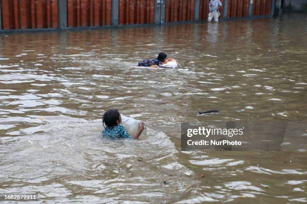 Children plays on a flooded road after heavy rains in Dhaka, Bangladesh on September 22, 2023.