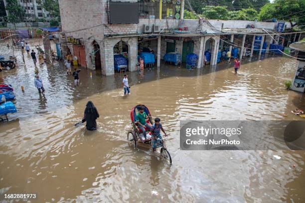 Commuters move through a water logged market amid heavy rains last night in Dhaka on September 22, 2023.