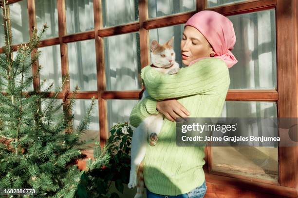 cancer survivor hugs her very happy cat in garden of her house - alopecia stockfoto's en -beelden