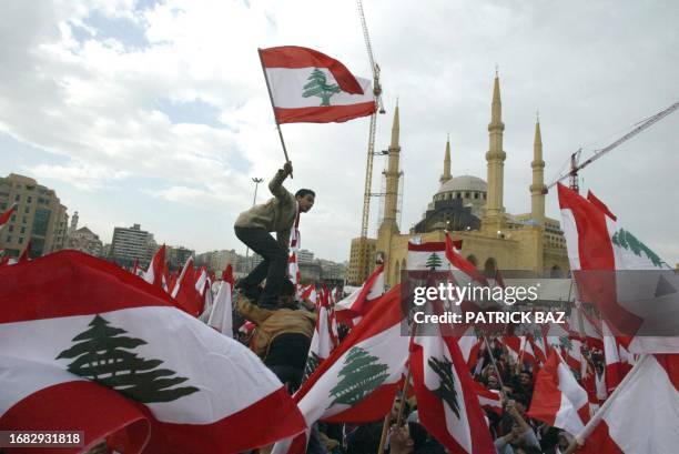 Lebanese pro-opposition demonstrators wave national flags as they gather in front central Beirut's Mohammed Al-Amin mosque, near the gravesite of...