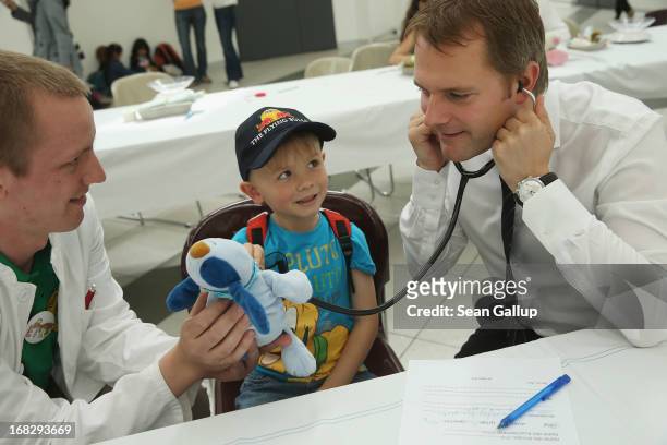 German Health Minister Daniel Bahr listens for a heartbeat of Maxeis, the blue teddy creature of Noel at the Teddy Bear Clinic at Charite Hospital on...