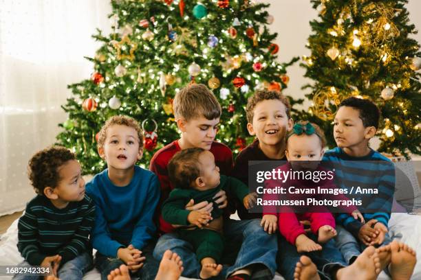 diverse large family with lots of children in front of christmas tree - sibling christmas stock pictures, royalty-free photos & images