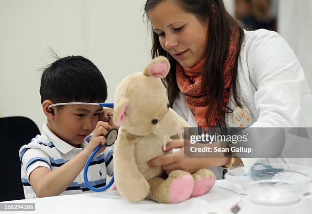 Medical student Alina Schwarz helps Phi Nam who was visiting with his mother, to diagnose his teddy bear at the Teddy Bear Clinic at Charite Hospital...