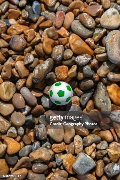 Miniature plastic football toy washed up on shingle beach, Shingle Street, Suffolk, England, UK,.